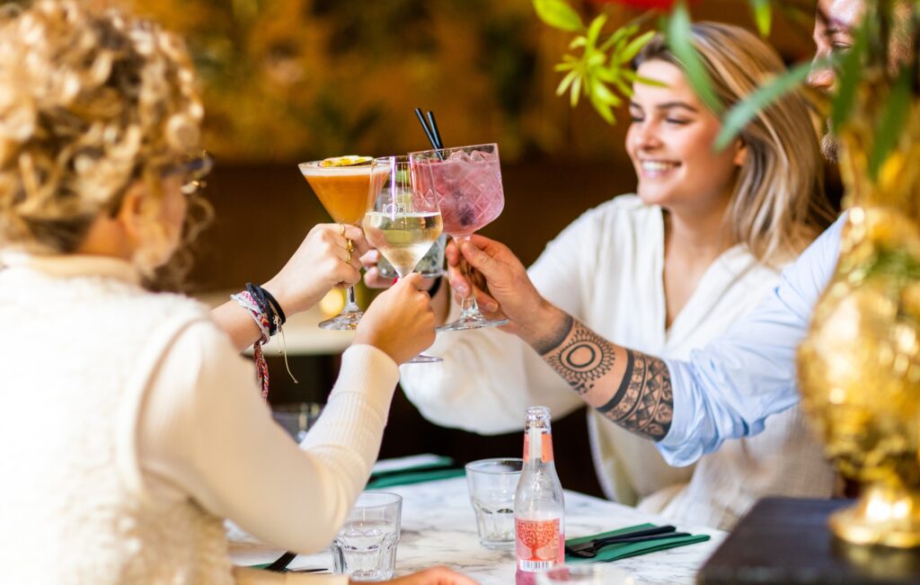 Een gezelschap van vier vrouwen zitten aan tafel bij Loev Deventer en proosten met hun drankjes.